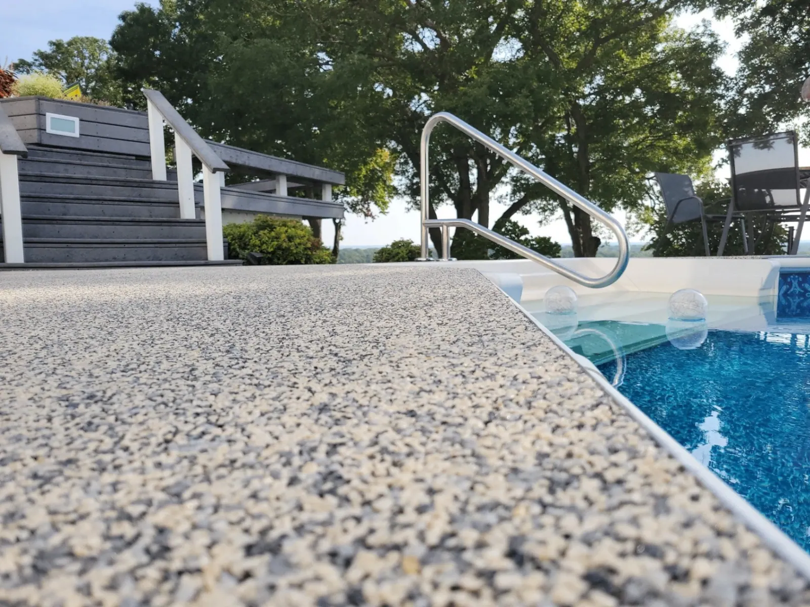 Close-up of resin bound stone surface beside a pool showing aggregate texture